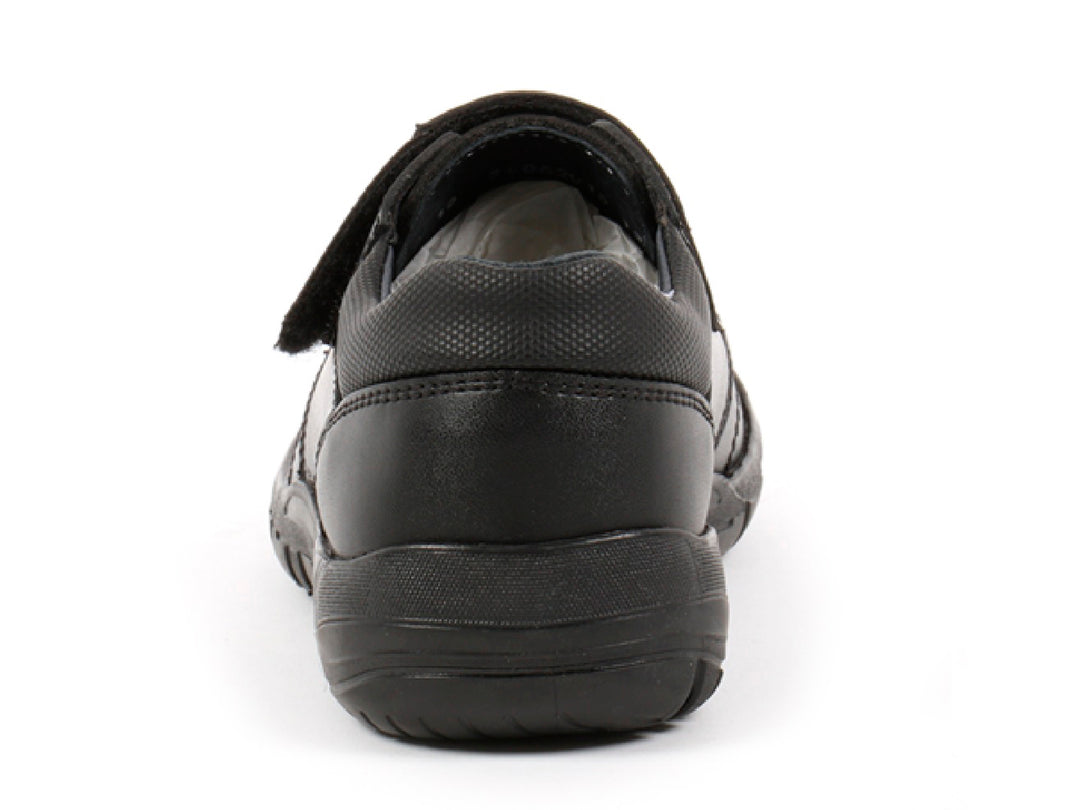 Par de zapatos negros para niño con cierre de velcro y detalles de costura roja.