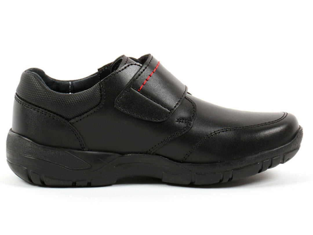 Par de zapatos negros para niño con cierre de velcro y detalles de costura roja.