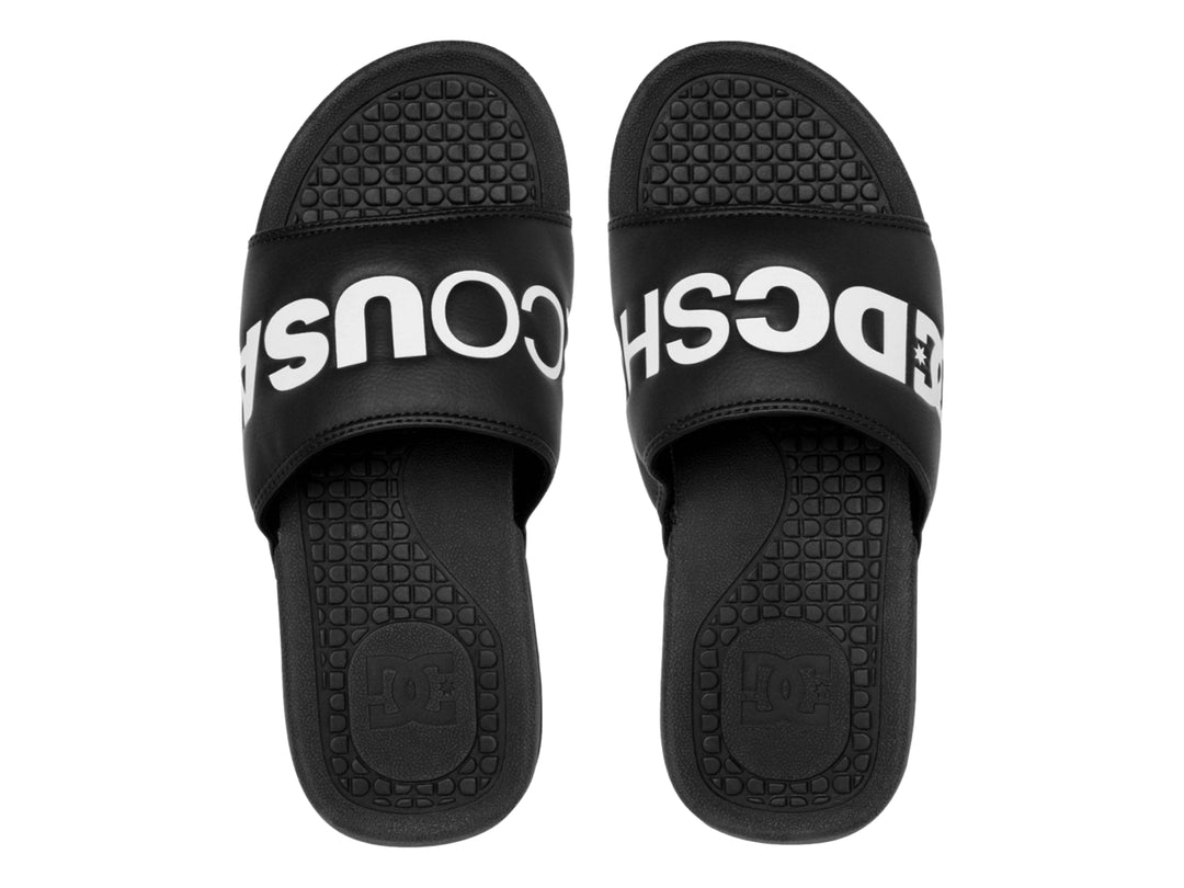 Sandalia tipo slide color negro con logotipo blanco de DC Shoes en la banda superior.