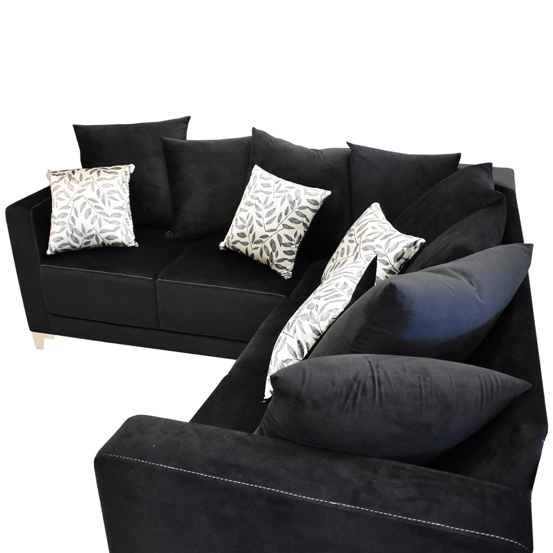 Sofá esquinero color negro con cojines decorativos estampados y patas doradas.