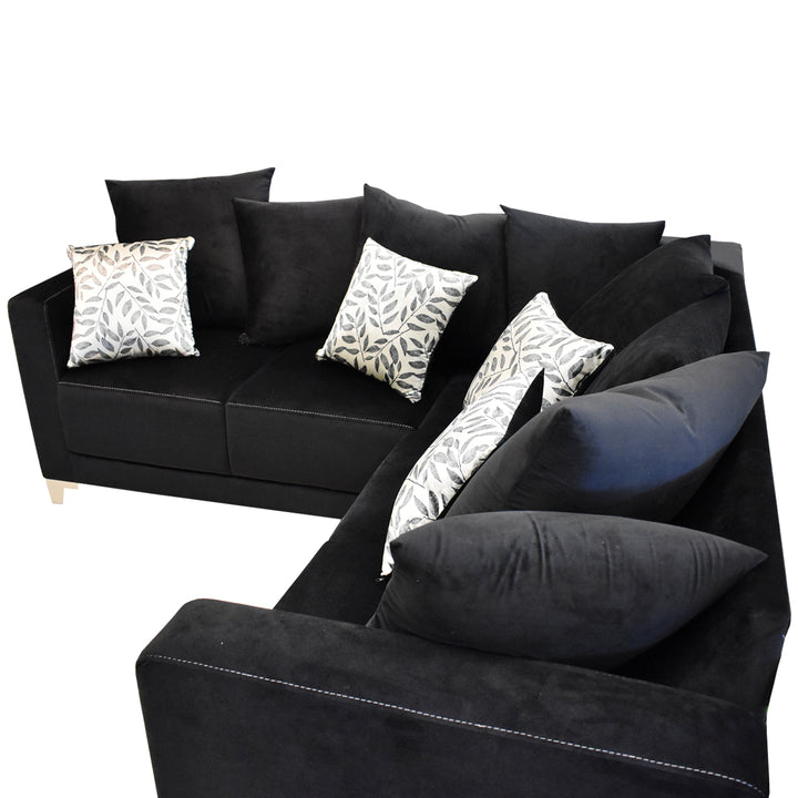 Sofá esquinero color negro con cojines decorativos estampados y patas doradas.