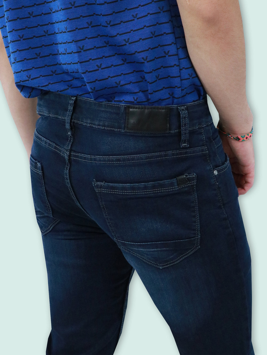 Jeans para hombre en color azul oscuro con efecto de lavado en los muslos y calzado blanco.