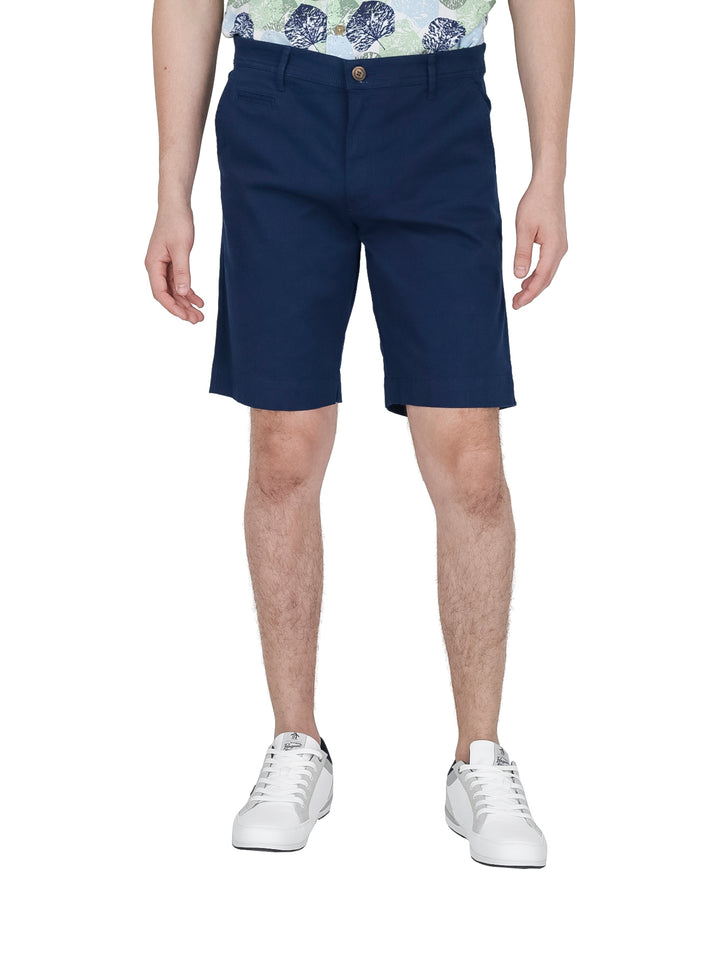 Hombre vistiendo bermudas color azul acero de la marca White Peak con tenis blancos.