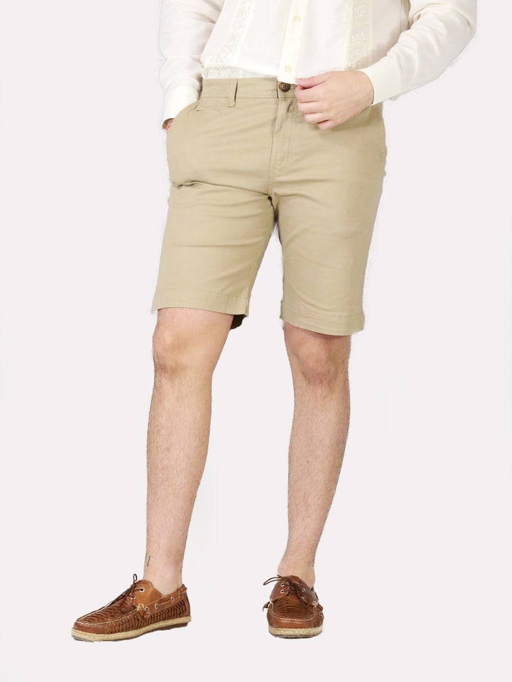 Hombre vistiendo bermudas color khaki, camisa blanca y zapatos cafés.