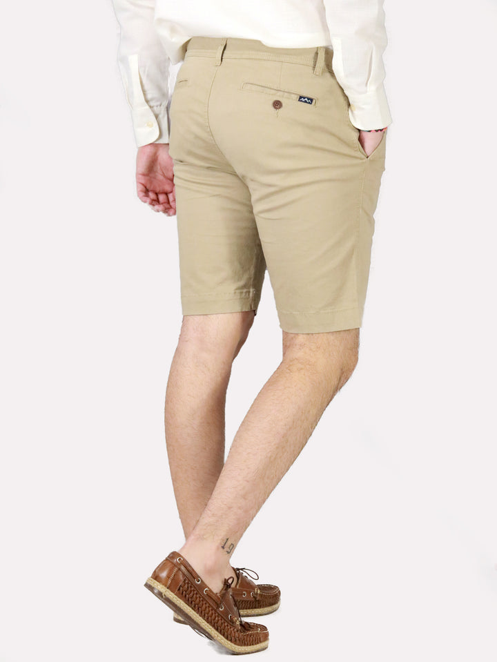 Hombre vistiendo bermudas color khaki, camisa blanca y zapatos cafés.