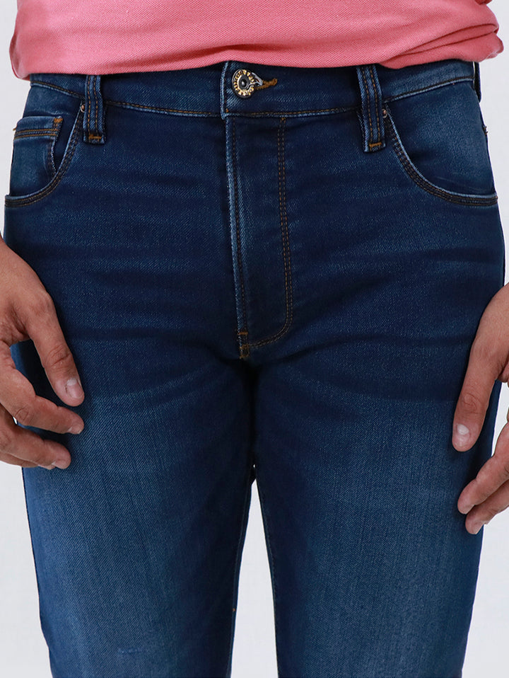 Primer plano de un pantalón de mezclilla azul oscuro para hombre con costuras doradas.