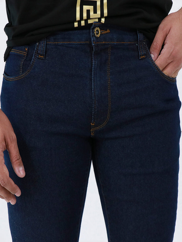 Detalle de pantalón de mezclilla azul oscuro para hombre con costuras en tono dorado.