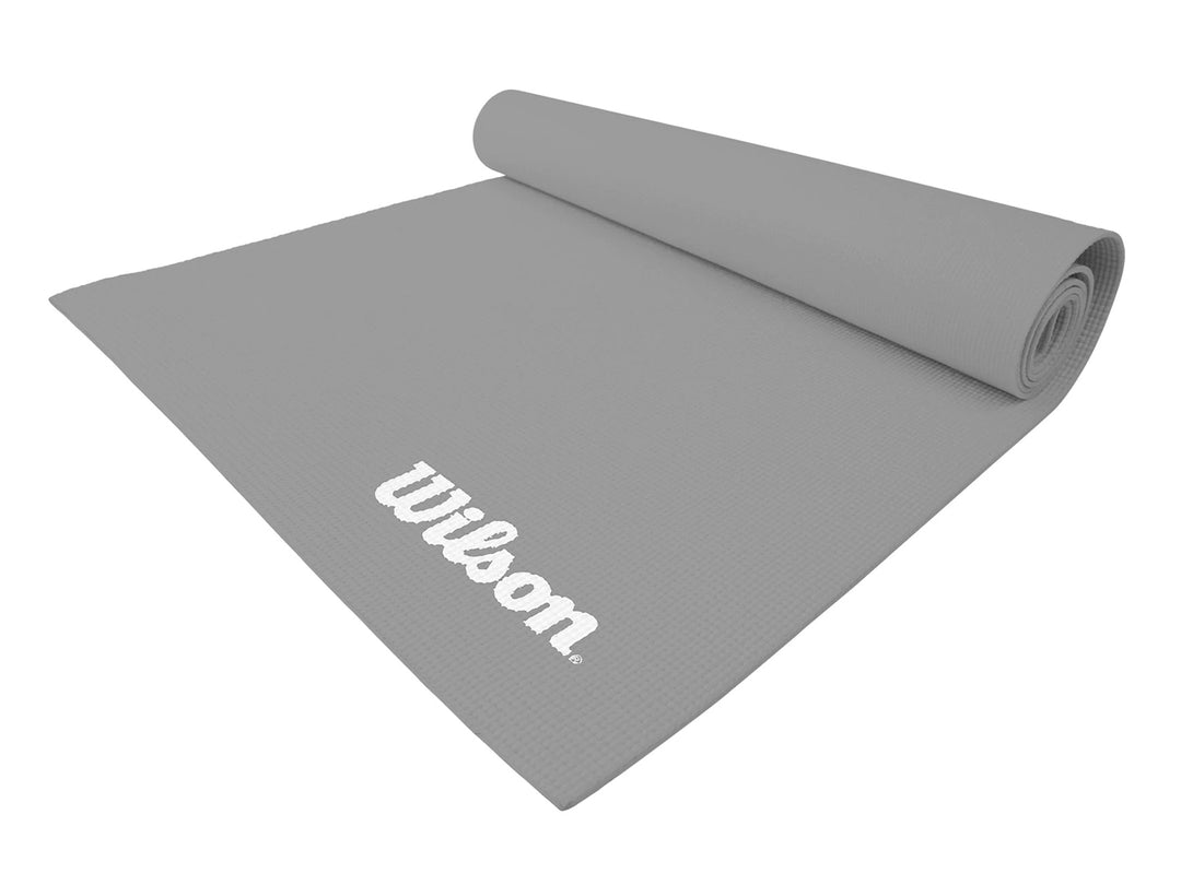 Tapete de yoga color gris de la marca Wilson, parcialmente enrollado sobre fondo blanco.