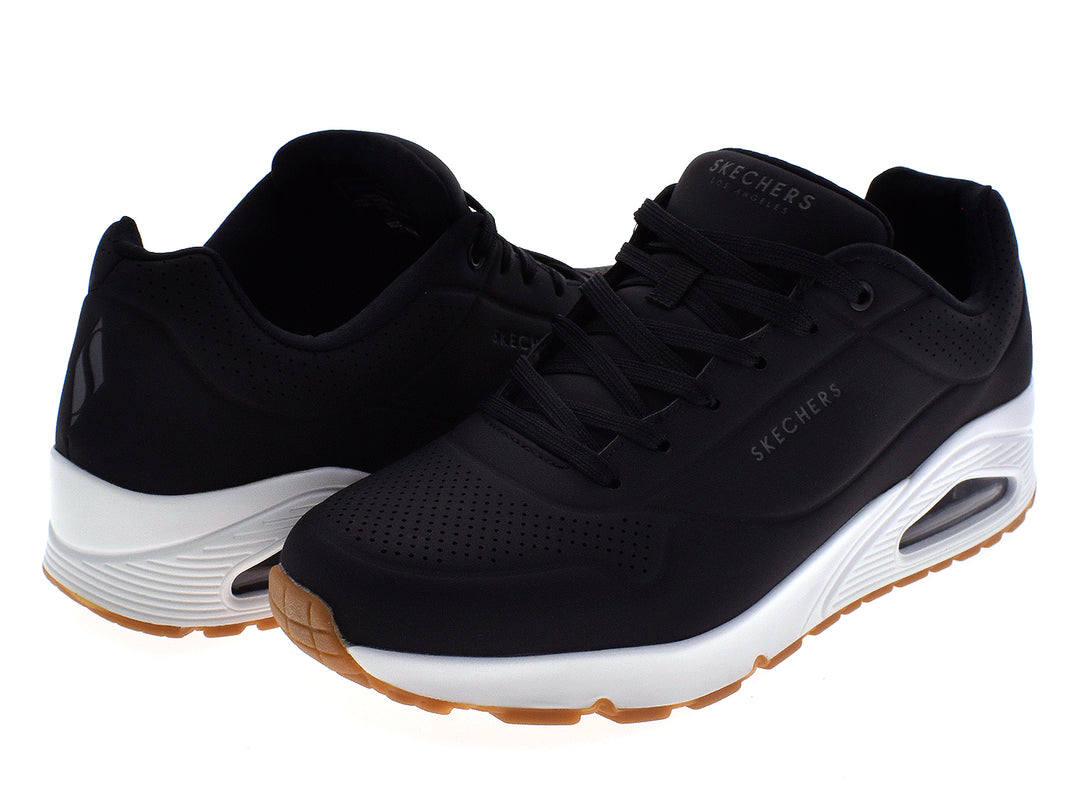 Tenis deportivos Skechers para hombre en color negro con suela blanca y beige.