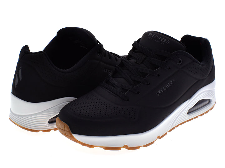 Tenis deportivos Skechers para hombre en color negro con suela blanca y beige.
