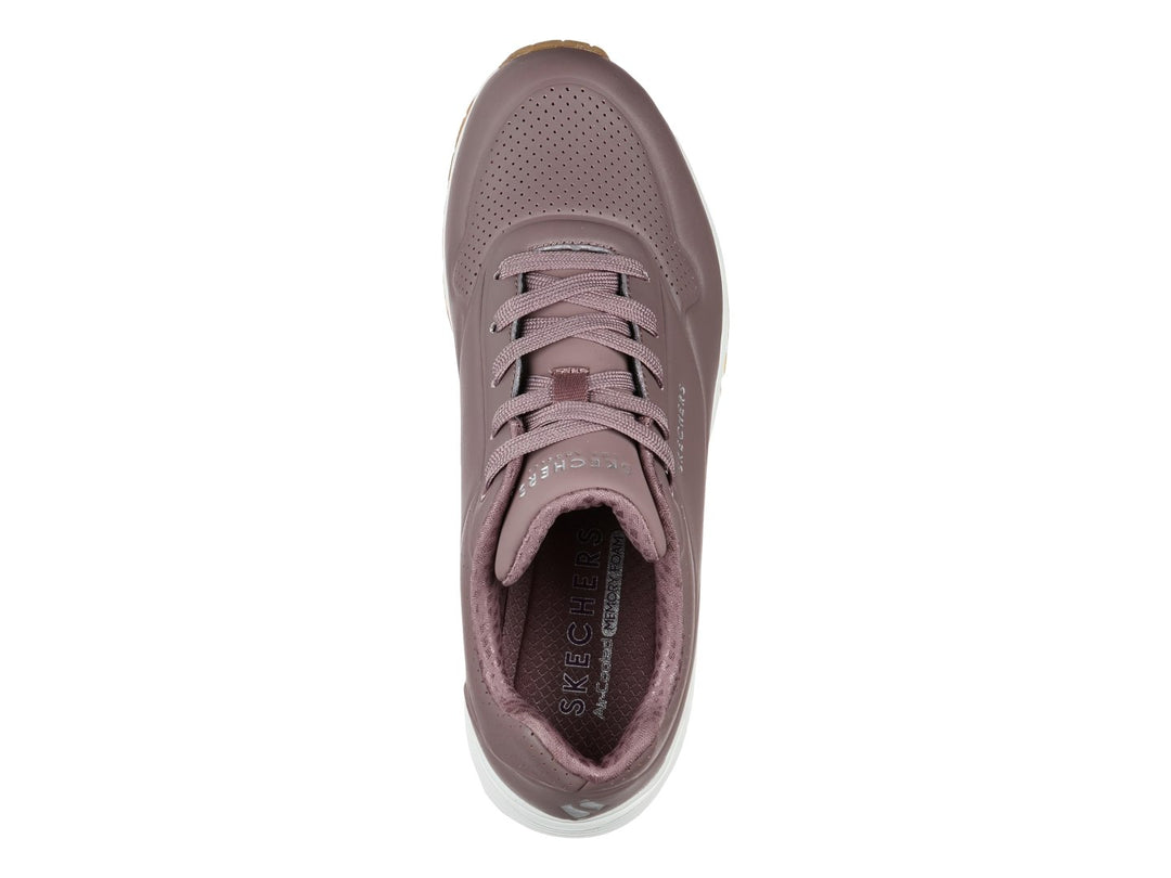 Tenis Skechers color malva con suela blanca y amortiguación visible, vista lateral.