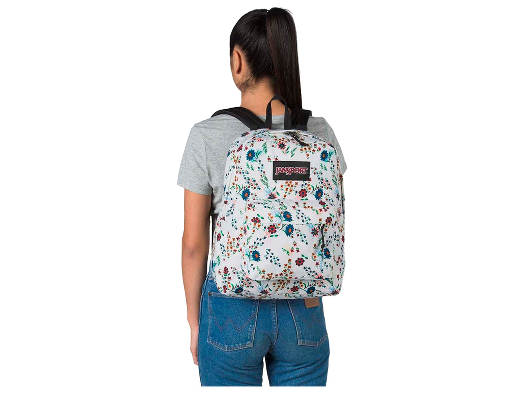 Mochila JanSport SuperBreak blanca con estampado floral multicolor y botella de agua en el bolsillo lateral.