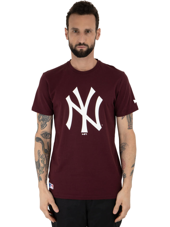 Hombre vistiendo una camiseta New Era de color morado oscuro con el logo de los New York Yankees en blanco.