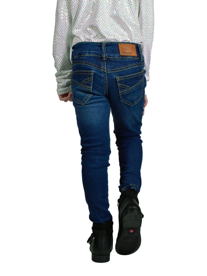 Jeans de mezclilla azul ajustados para niña combinados con botas negras.