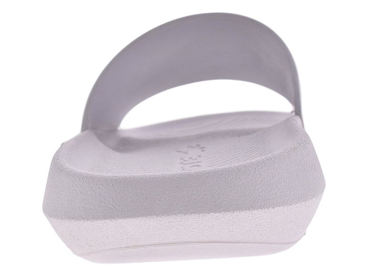 Sandalia slide blanca de la marca Lacoste con logo verde en la banda superior.