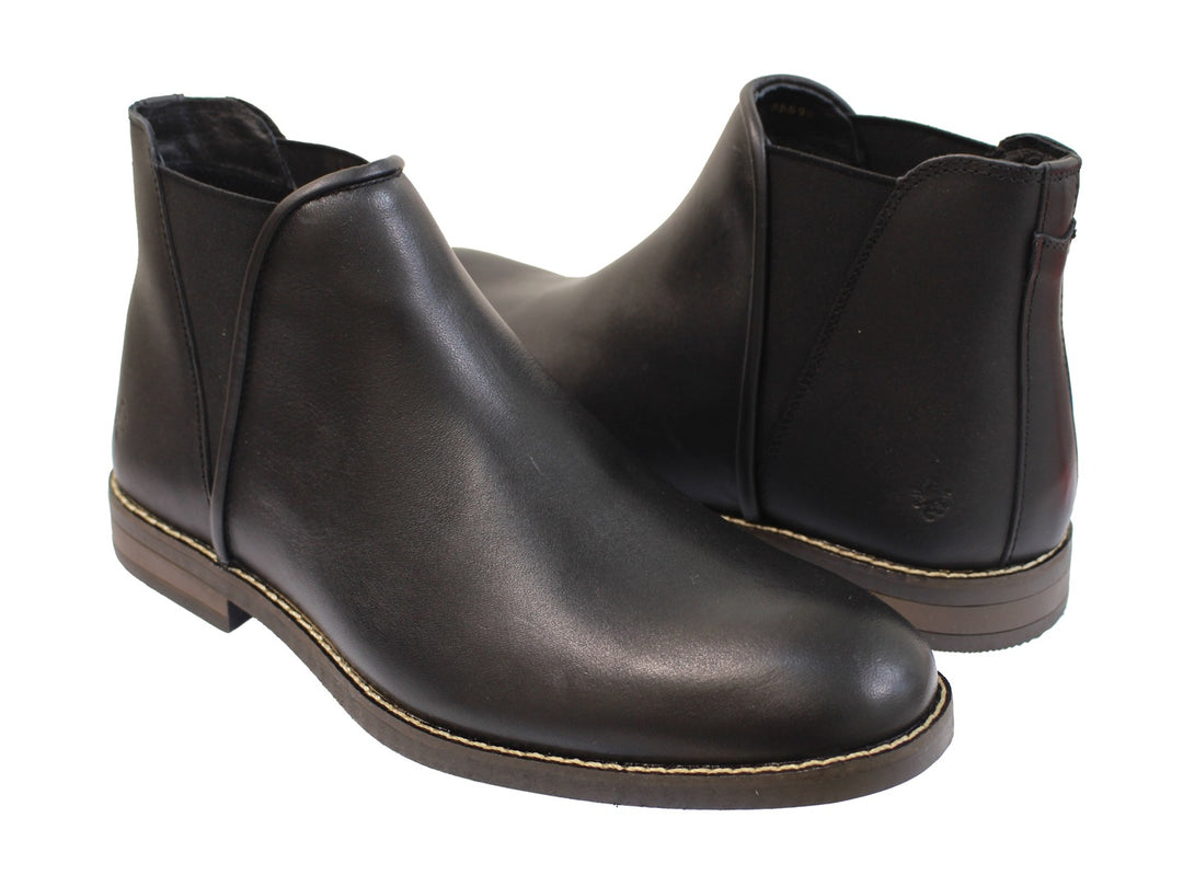 Botas negras para hombre de cuero con costuras claras en la suela sobre fondo blanco.