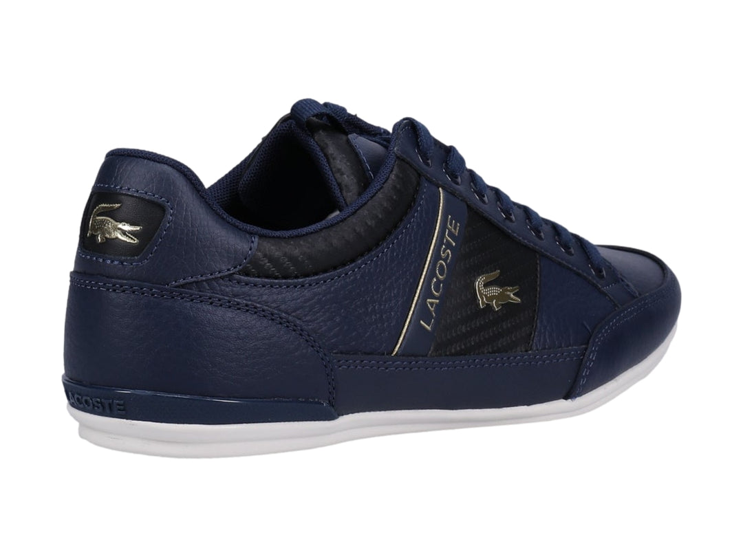 Tenis Lacoste color azul marino y negro con suela blanca y detalles dorados.