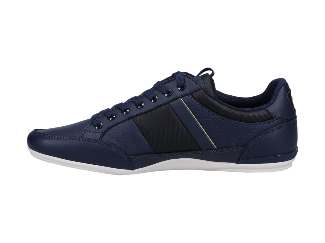 Tenis Lacoste color azul marino y negro con suela blanca y detalles dorados.