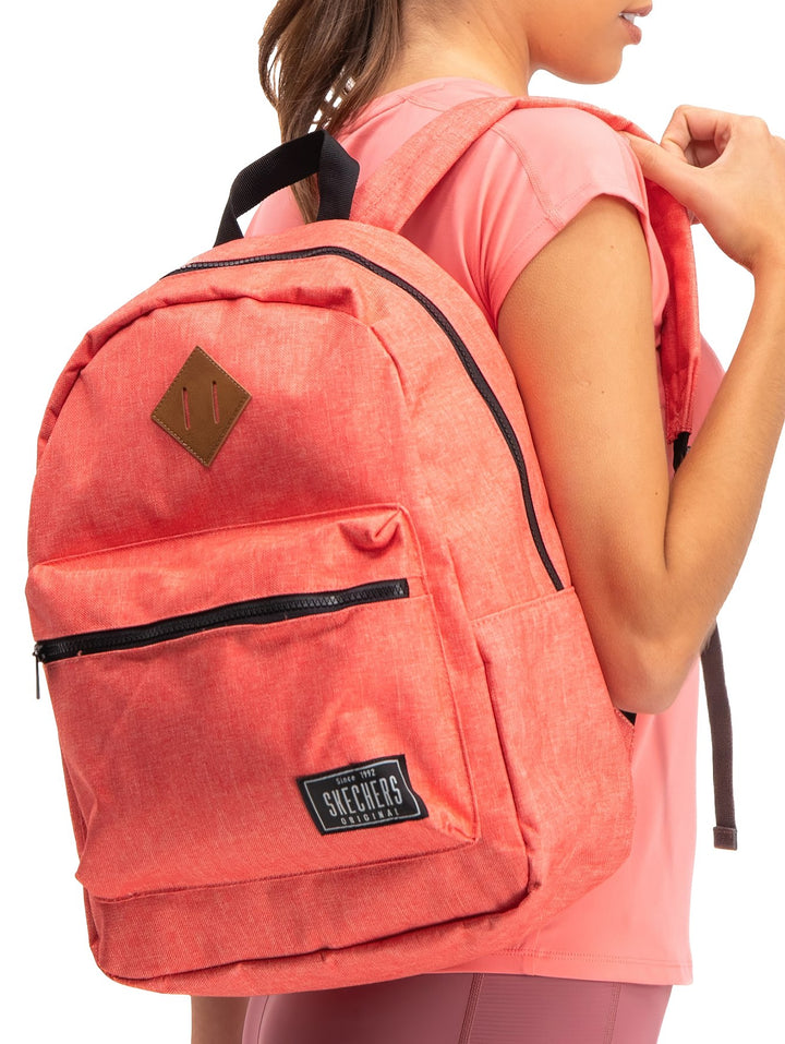 Mochila escolar Skechers color coral con detalles en negro y un parche marrón decorativo.