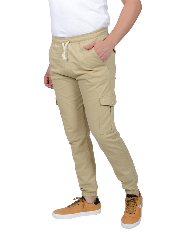 Hombre vistiendo pantalones joggers color khaki con bolsillos laterales y cargo, calzado casual color miel.
