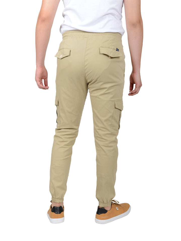 Hombre vistiendo pantalones joggers color khaki con bolsillos laterales y cargo, calzado casual color miel.