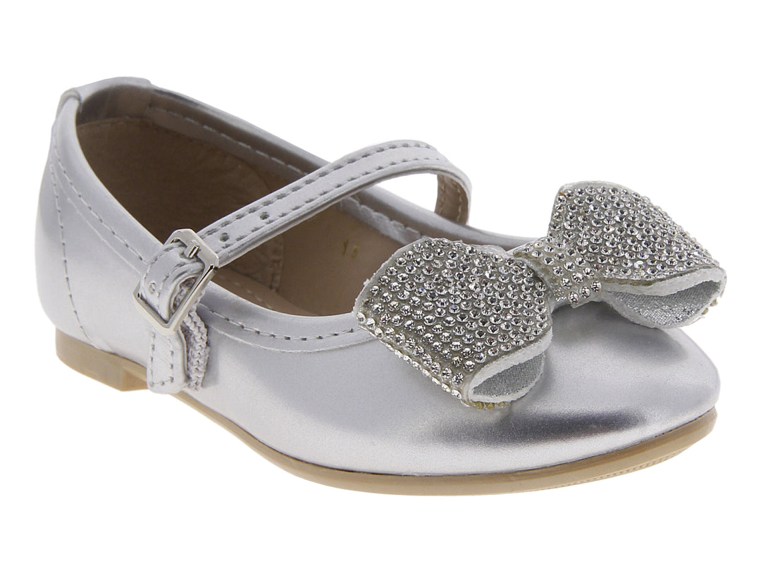 Zapato plano color plata para niña con moño brillante y correa con hebilla.