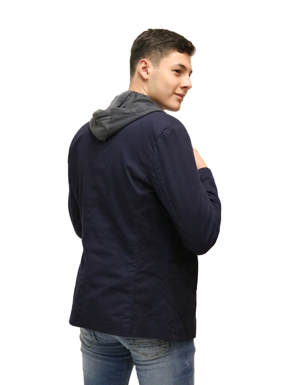Hombre vistiendo un saco color marino con capucha gris, playera blanca y jeans azules.
