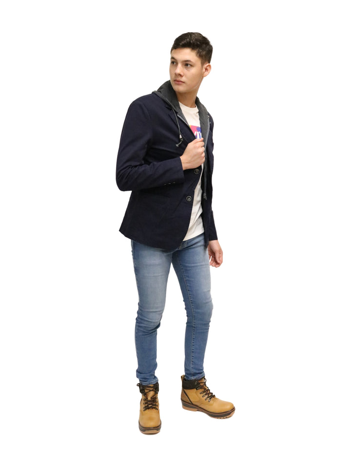 Hombre vistiendo un saco color marino con capucha gris, playera blanca y jeans azules.
