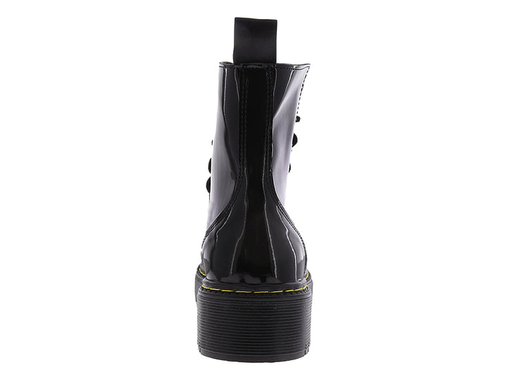Bota de combate negra brillante con suela track y costuras amarillas.