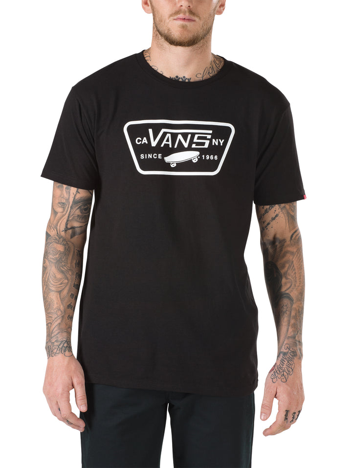 Hombre vistiendo playera negra de manga corta con logotipo blanco de Vans en el pecho.