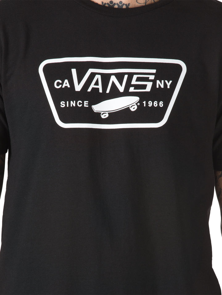 Hombre vistiendo playera negra de manga corta con logotipo blanco de Vans en el pecho.
