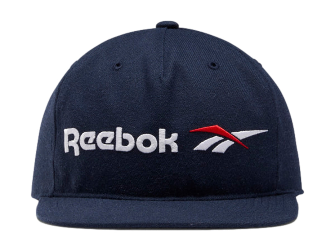 Gorra Reebok de color azul marino con visera plana y logotipo blanco y rojo en el frente.