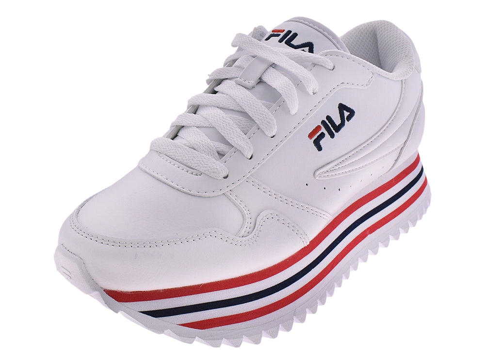 Tenis FILA blancos con detalles de rayas rojas y azules en la suela y base dentada.