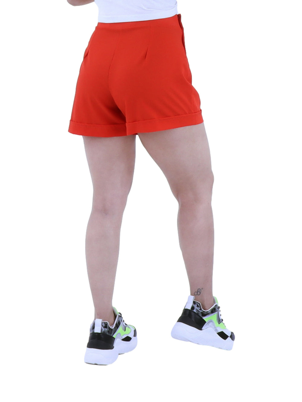 Mujer vistiendo short rojo de cintura alta con tenis deportivos sobre fondo blanco.