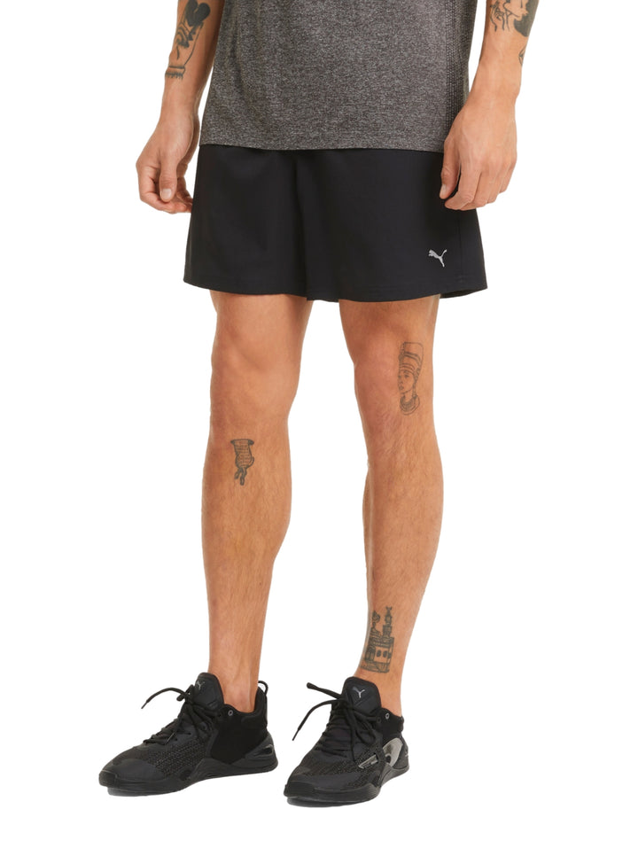 Hombre vistiendo shorts deportivos PUMA de color negro, corte corto y tejido técnico.