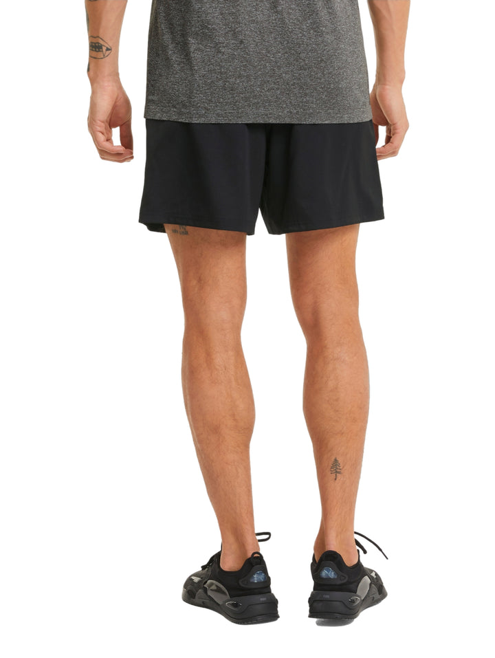 Hombre vistiendo shorts deportivos PUMA de color negro, corte corto y tejido técnico.