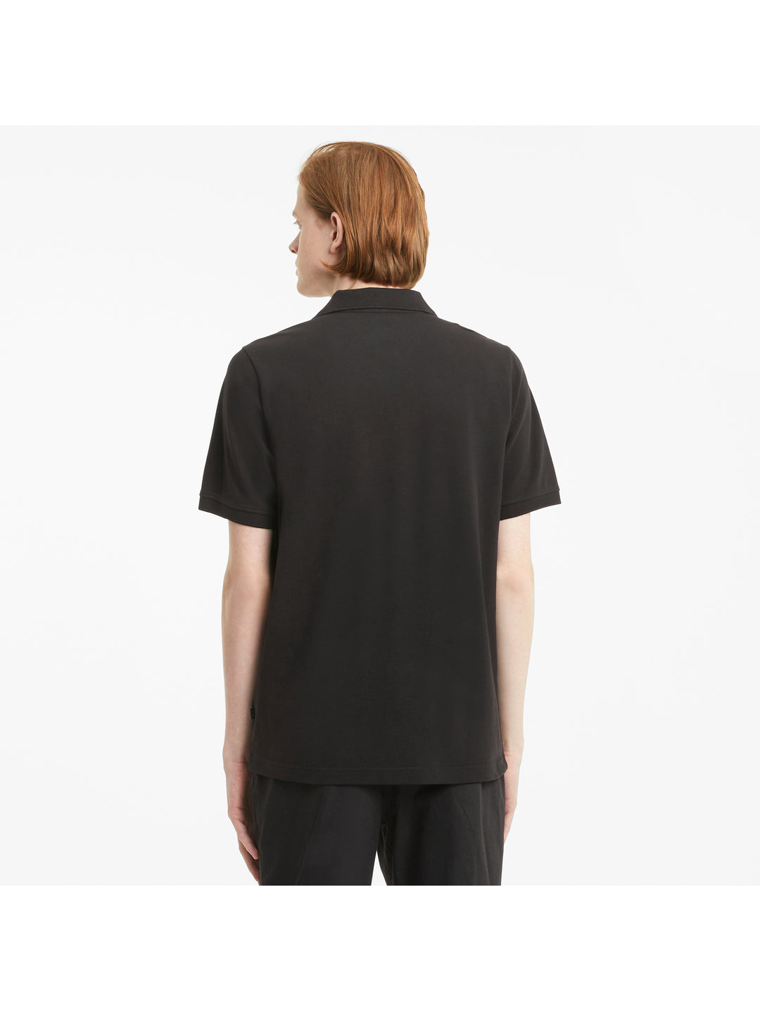 Hombre vistiendo una playera polo PUMA de color negro con logotipo blanco en el pecho.