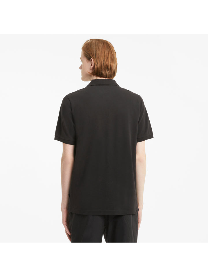 Hombre vistiendo una playera polo PUMA de color negro con logotipo blanco en el pecho.