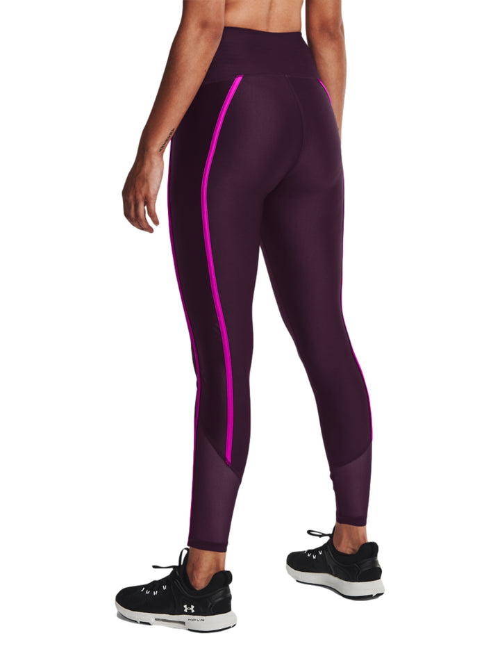 Mujer vistiendo mallas deportivas Under Armour color morado con franjas laterales en rosa brillante.