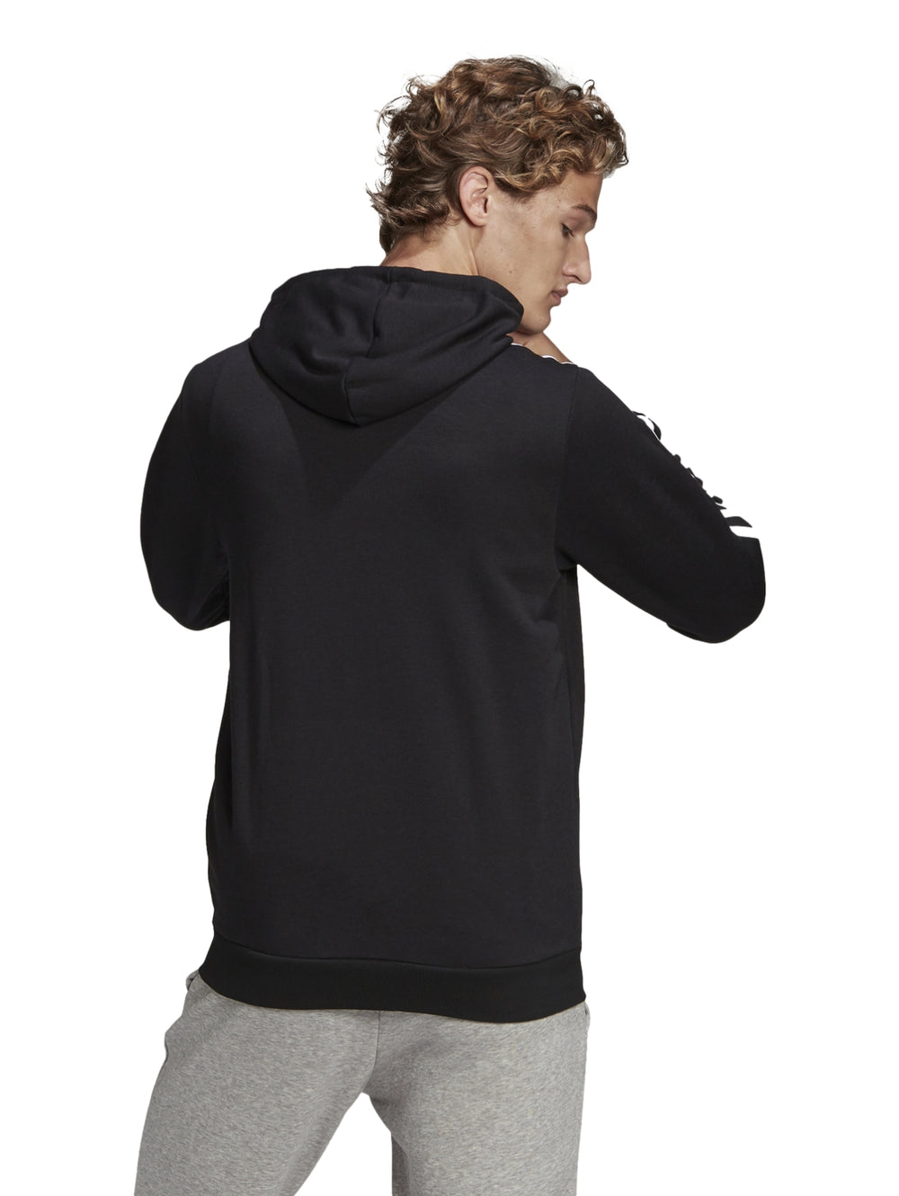 Hombre vistiendo sudadera deportiva Adidas negra con capucha, cierre completo y tres franjas blancas en las mangas.