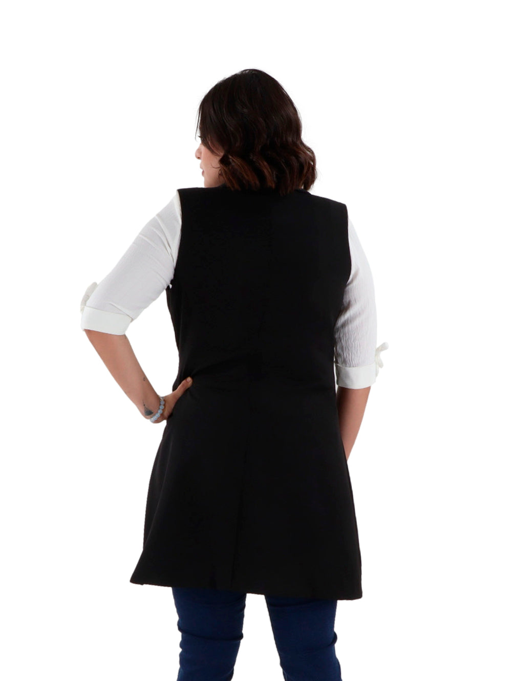 Mujer vistiendo un chaleco largo color negro con hebilla dorada en la cintura sobre una camisa blanca.