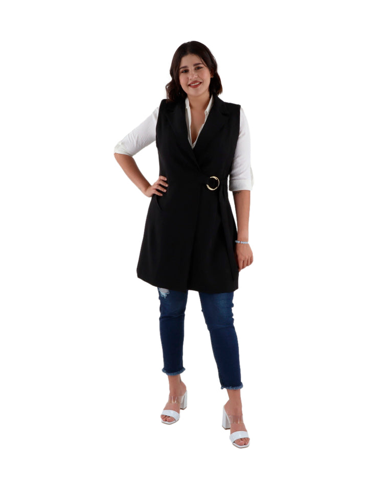 Mujer vistiendo un chaleco largo color negro con hebilla dorada en la cintura sobre una camisa blanca.