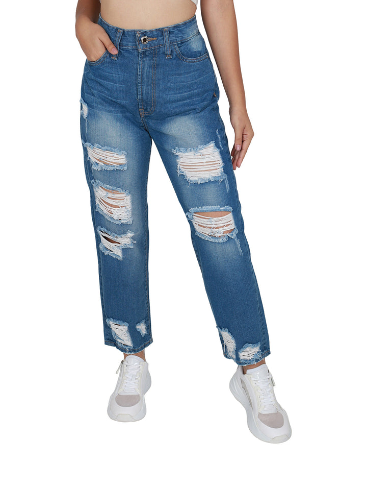 Pantalones jeans azules de mezclilla con roturas decorativas y calzado blanco.