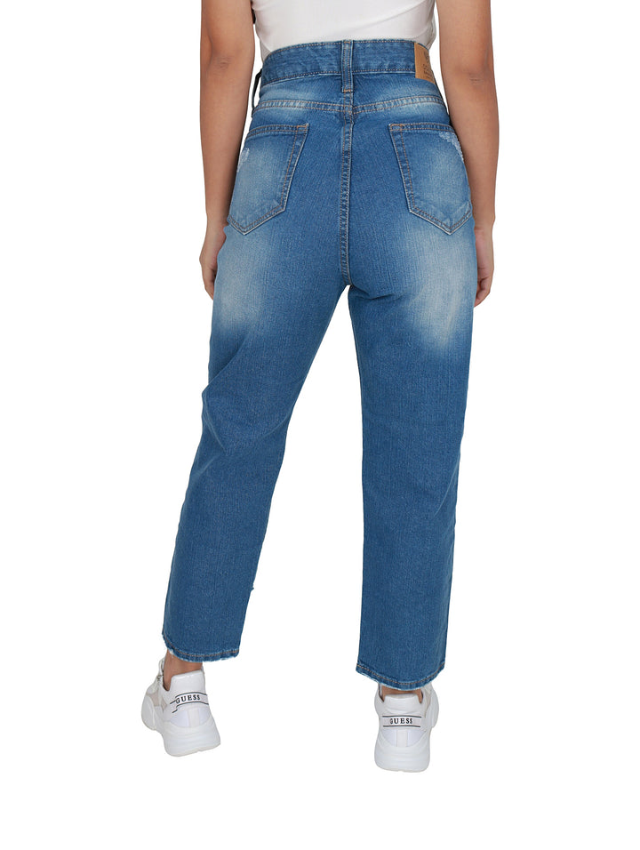 Pantalones jeans azules de mezclilla con roturas decorativas y calzado blanco.