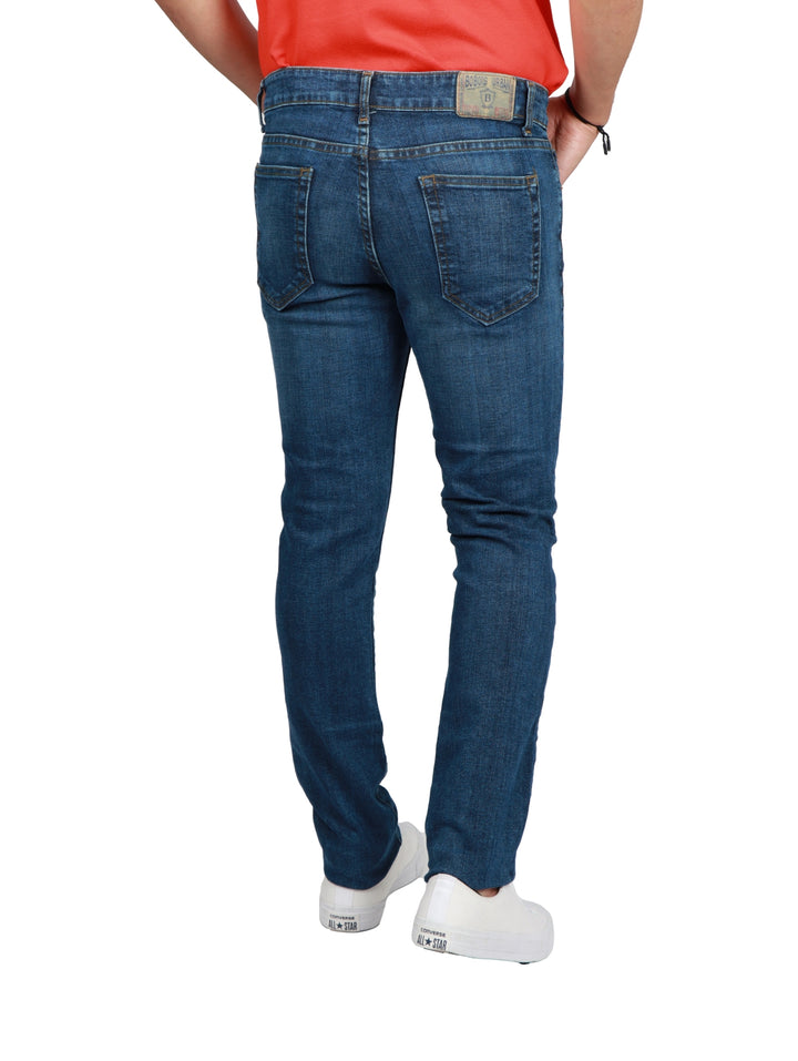 Jeans azul oscuro de corte slim para hombre con calzado blanco.