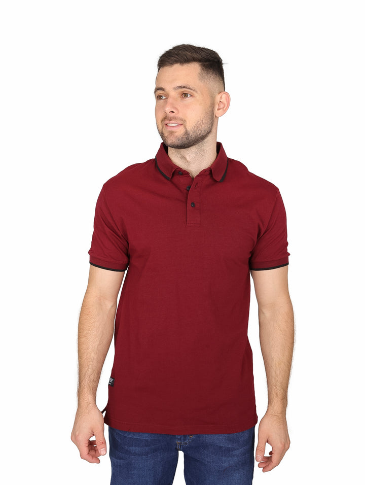 Hombre vistiendo playera polo color vino con detalles negros en cuello y mangas.