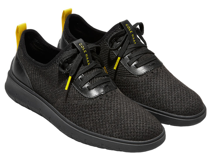Tenis negros Cole Haan Generation Zerogrand Stitchlite para hombre con detalles amarillos.