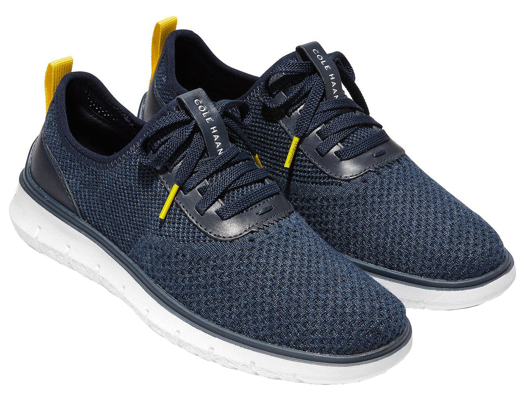 Tenis deportivos Cole Haan color azul marino con suela blanca y detalles en amarillo.