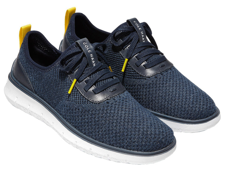 Tenis deportivos Cole Haan color azul marino con suela blanca y detalles en amarillo.