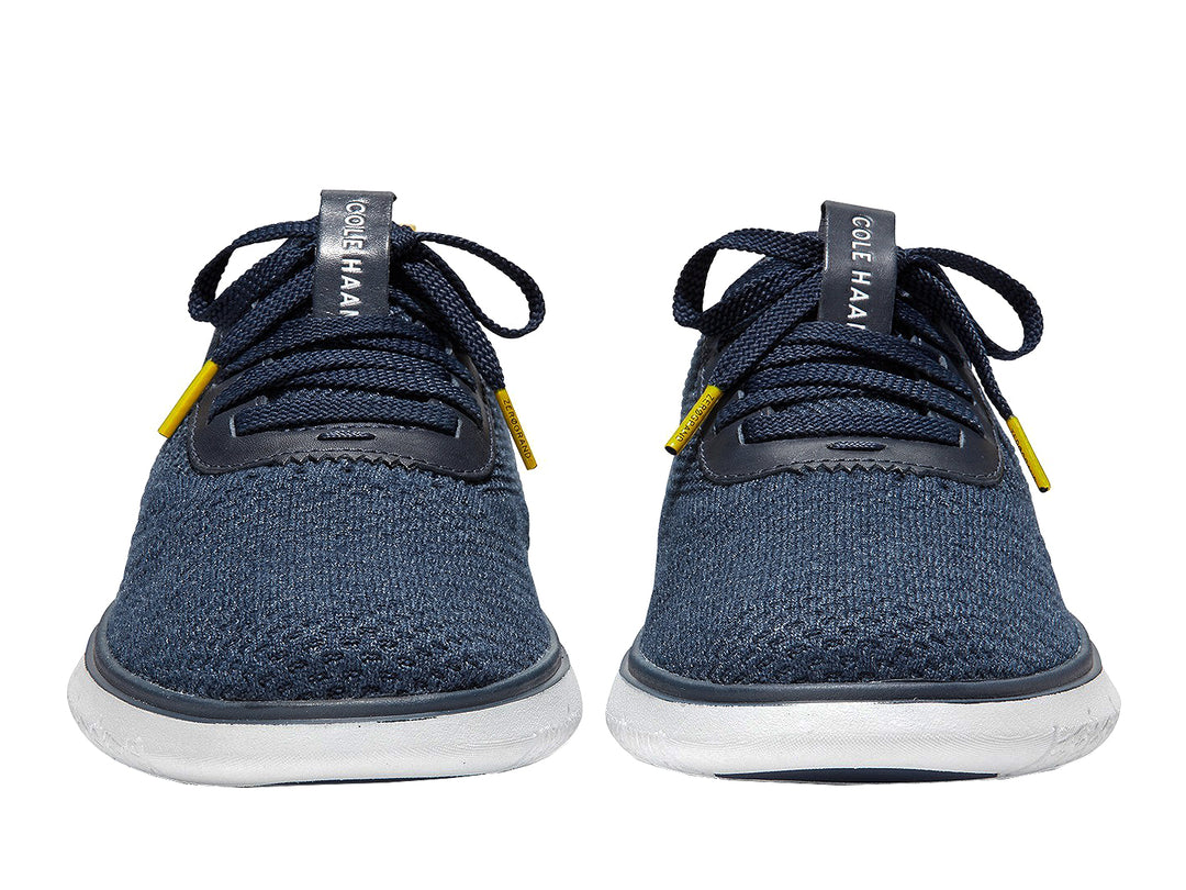 Tenis deportivos Cole Haan color azul marino con suela blanca y detalles en amarillo.